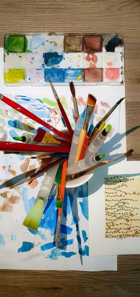 A vibrant artist's workspace with various paint brushes and a watercolor palette.